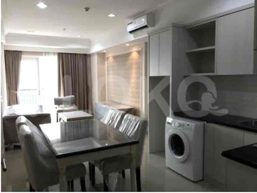 A bright dining area with a table and chairs next to a kitchen area with a washing machine.