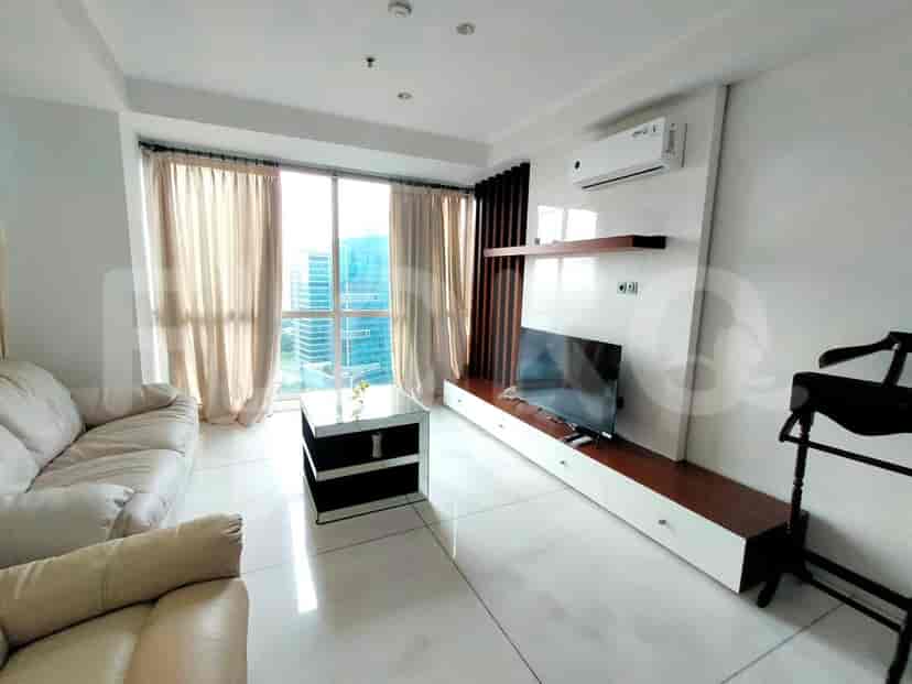 A modern living room with a sofa, TV, and large window.