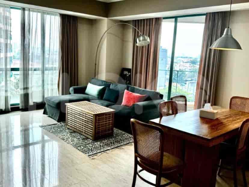 A well-lit living room with a grey sofa, wooden coffee table, dining table and large windows.