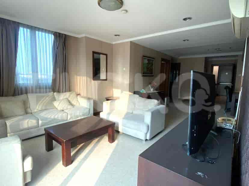 Living area with light-colored sofas, coffee table, and a TV console.