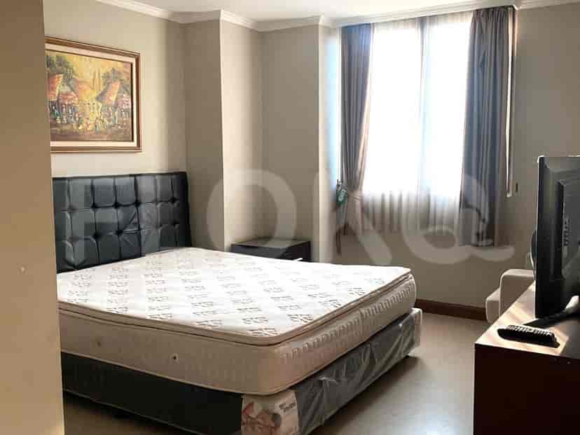 A bedroom with a queen bed, artwork and a TV.