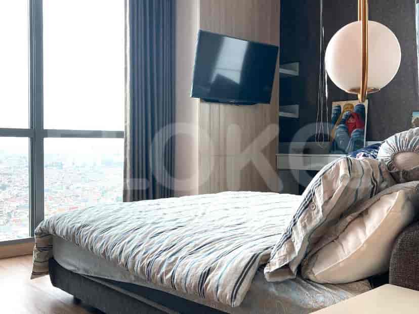 A bedroom with a bed, a wall-mounted TV, and a large window offering a city view.