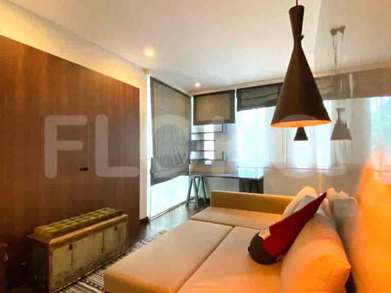 Ruang tamu dengan sofa, meja, dan lampu gantung.