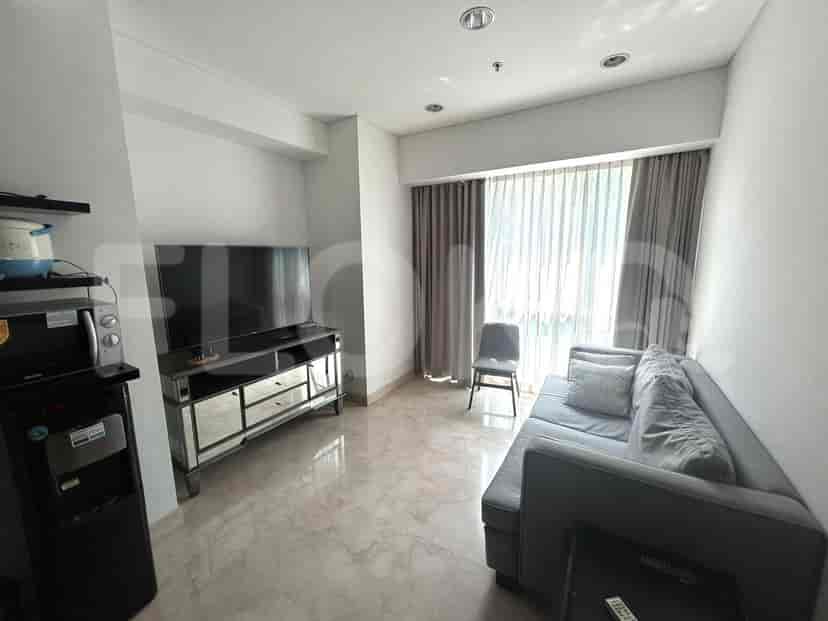 A well-lit living room featuring a mirrored TV stand, grey sofa, and large window.