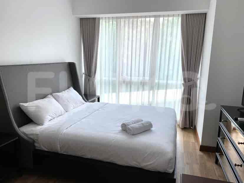 A well-lit bedroom featuring a queen-sized bed and large window.