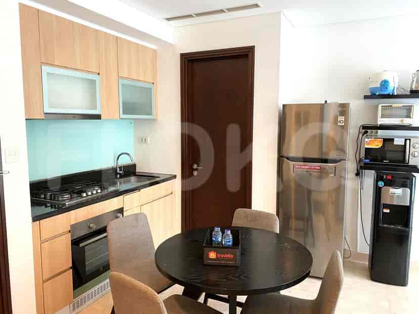 A modern kitchen featuring light wooden cabinets, a stainless steel refrigerator, and a dining table.