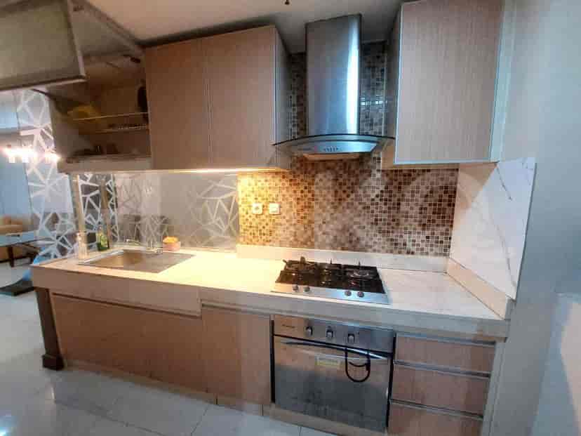 Well-equipped kitchen with wooden cabinets, a gas stove, and a stainless steel chimney.