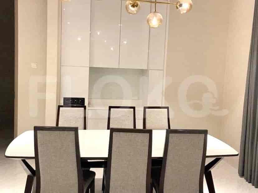 A bright dining area with a long white table and stylish chairs.