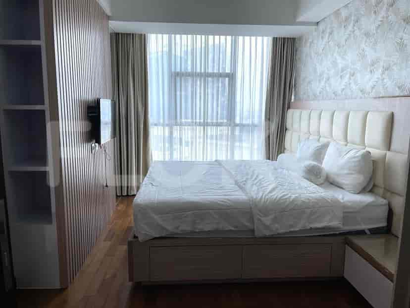 Cozy bedroom with a large bed, wooden flooring, and sheer curtains.
