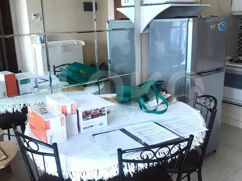 Area makan dengan meja, kursi, dan lemari es.