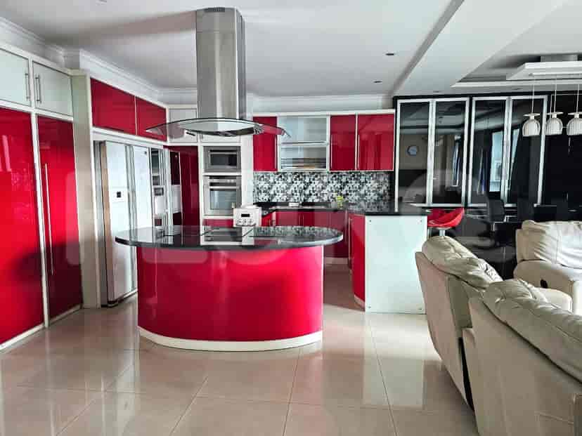 Open-plan living area with a red and white kitchen.