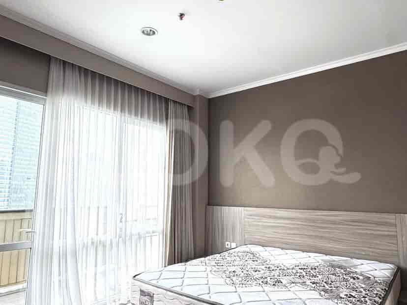 A bedroom with a double bed, neutral-toned walls, and sheer curtains.