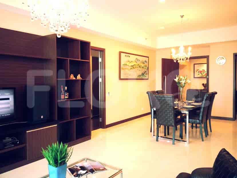 Ruang tamu dan area makan yang terang dengan perabotan modern, menampilkan pusat hiburan built-in, meja makan, dan lampu gantung dekoratif.