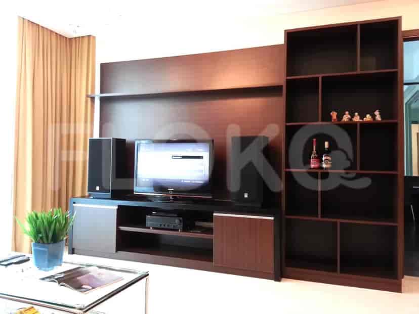Ruang tamu dengan unit hiburan built-in, TV, dan rak untuk pajangan dan penyimpanan.