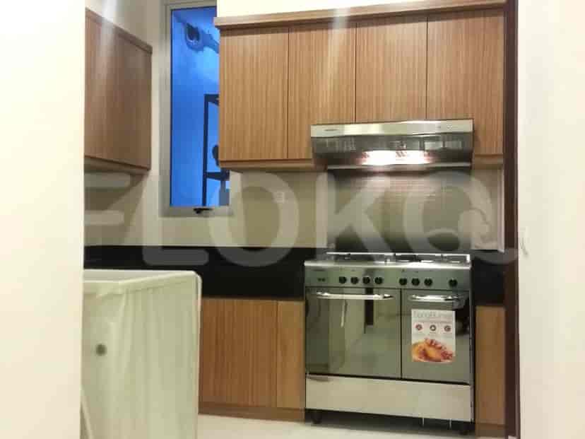 Dapur ringkas dengan lemari kayu, kompor gas, dan tudung range.