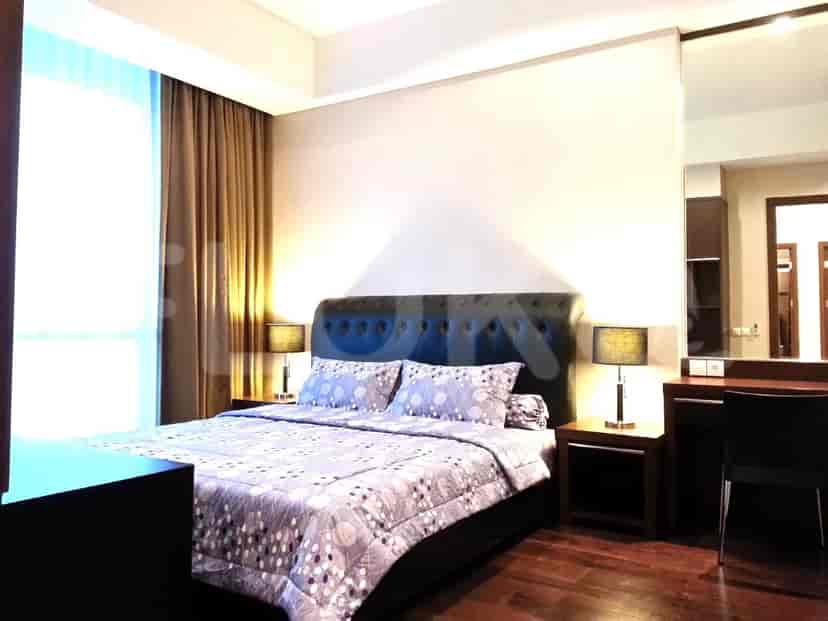 Kamar tidur kontemporer dengan tempat tidur besar, meja samping tempat tidur, dan meja rias dengan cermin.