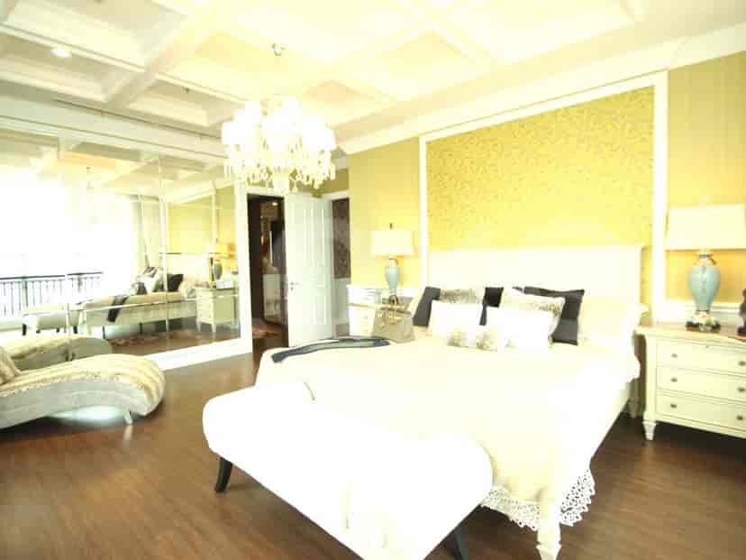 A luxurious bedroom with a large bed, seating area, and a mirror.
