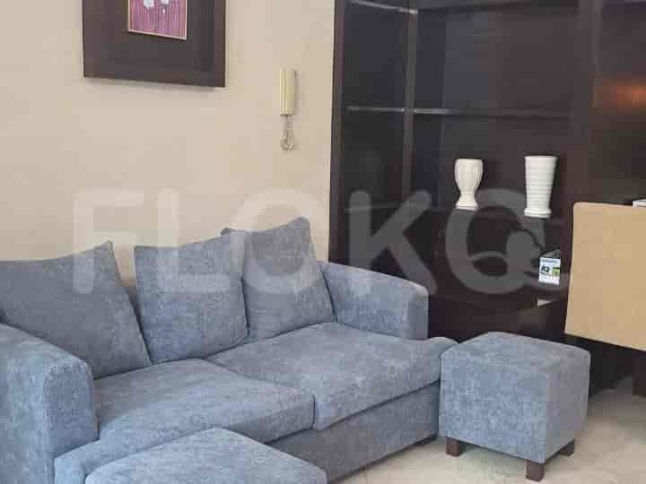 Ruang tamu dengan sofa sectional abu-abu, ottoman, dan unit rak built-in.