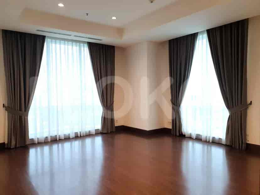 An empty room with large windows draped with curtains, offering a bright and open feel.