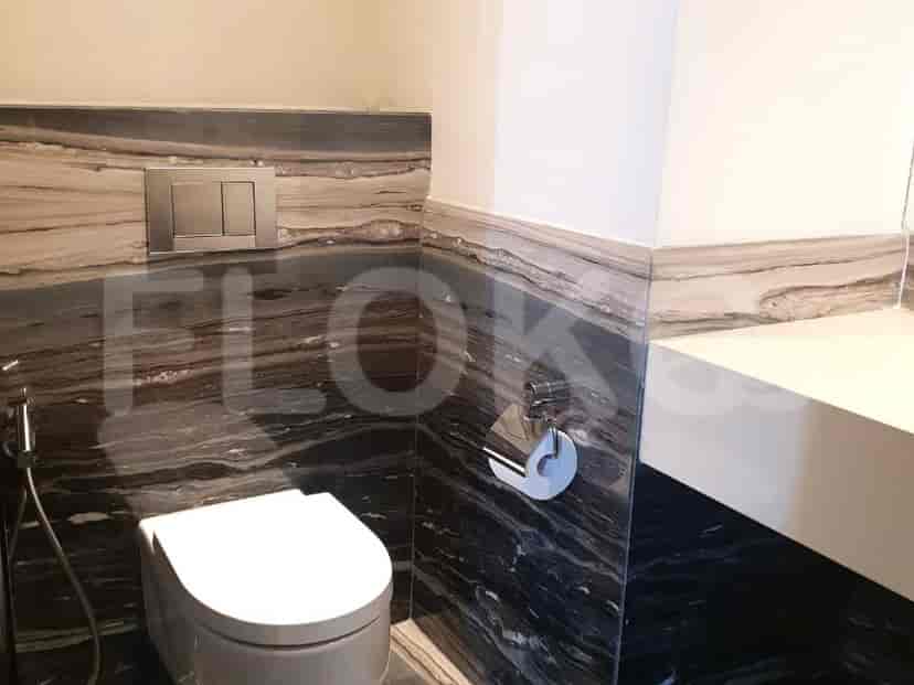 A modern bathroom with marble accents, a toilet, and a wall-mounted faucet.