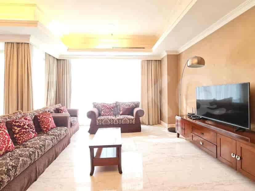 A luxurious living room with patterned sofas, a large TV, and elegant decor.