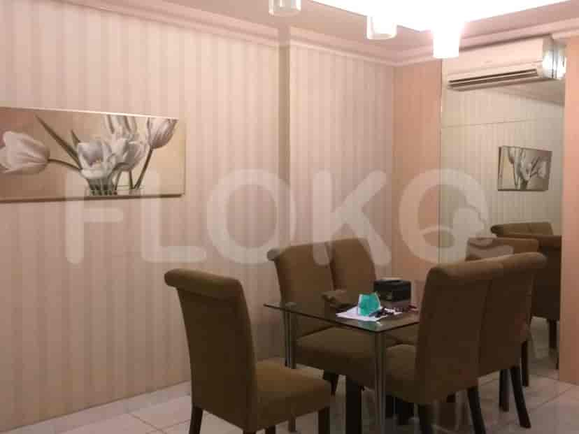 Dining area with a glass table and chairs, and a floral painting.