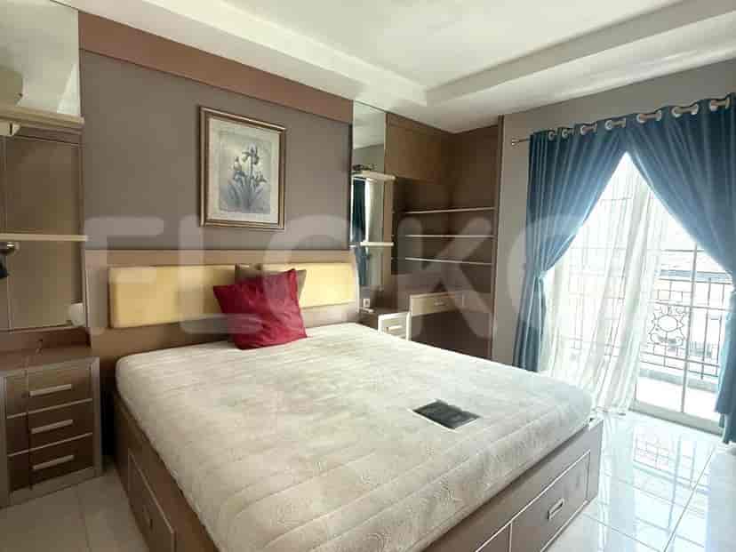 A bedroom featuring a bed, cabinet, and a large window.