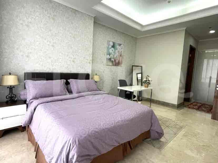 A bedroom with a bed, nightstand and a work desk.