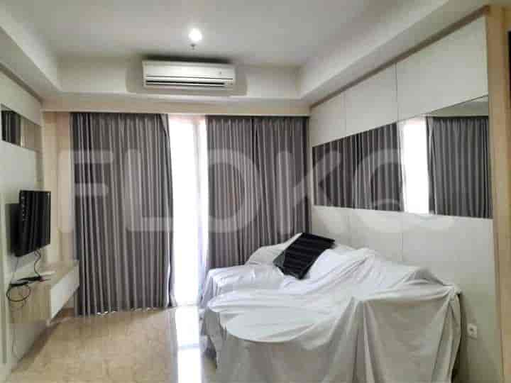 Ruang tamu dengan sofa tertutup, TV, dan jendela.
