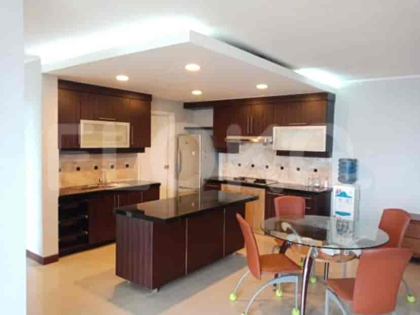 Modern kitchen with dark wooden cabinetry, a central island, and a dining area with a glass table.