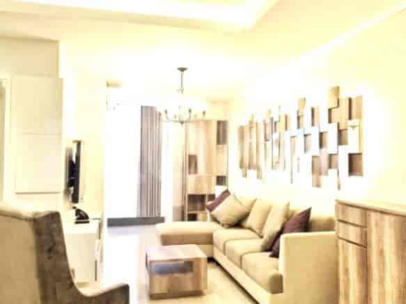 A well-lit living area with a beige sectional sofa, decorative wall art, and a wooden coffee table.