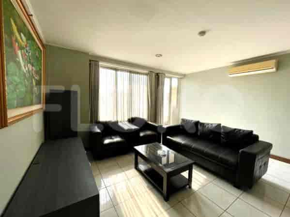 A living room featuring black leather sofas, a glass coffee table, and a painting.