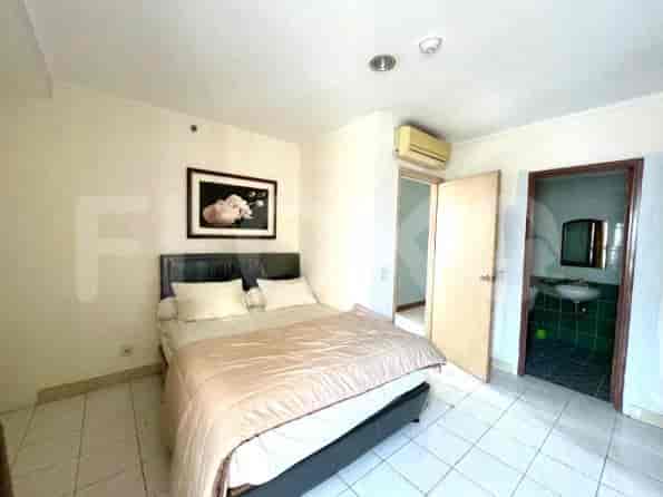 A bedroom with a double bed, a framed picture, and a doorway leading to a bathroom.