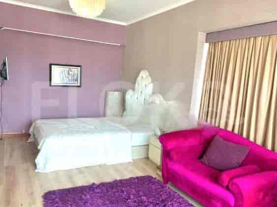 Kamar tidur dengan tempat tidur, sofa merah muda, dan karpet ungu.