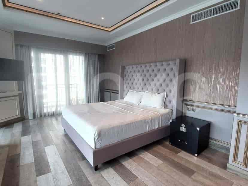 Kamar tidur yang terang dengan sandaran kepala berumbai dan lantai kayu.