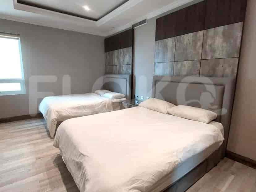 Kamar tidur dengan dua tempat tidur dan palet warna netral.