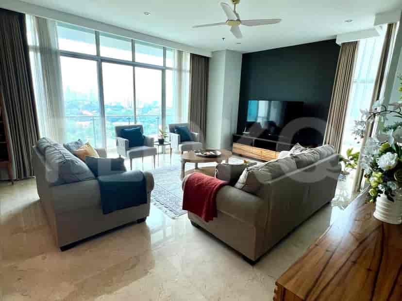 Ruang tamu dengan sofa abu-abu, TV, dan jendela besar dengan pemandangan kota.