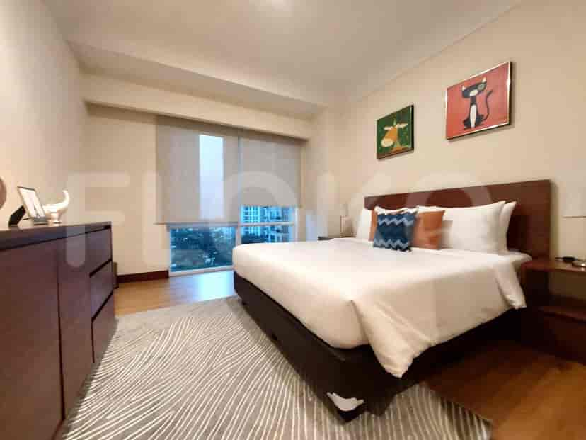 A cozy bedroom with a bed, large window, and artwork.