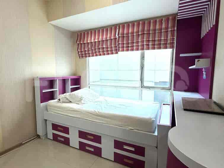 A small bedroom with a single bed with white sheets and colorful drawer.