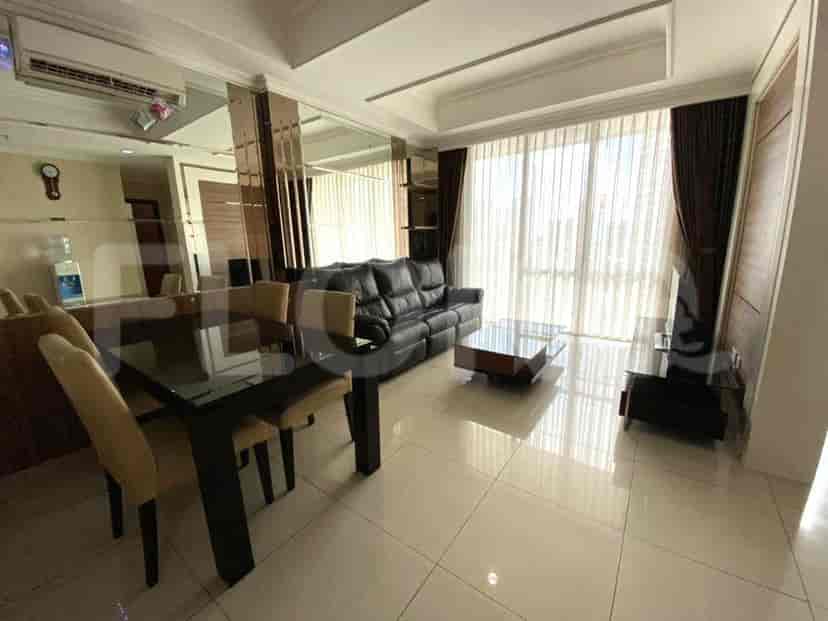 Modern living room with black leather sofa, dining area, and large windows.