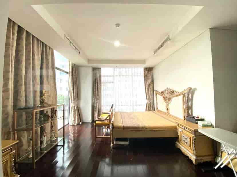 A bedroom with a large bed, bedside tables, and curtains.