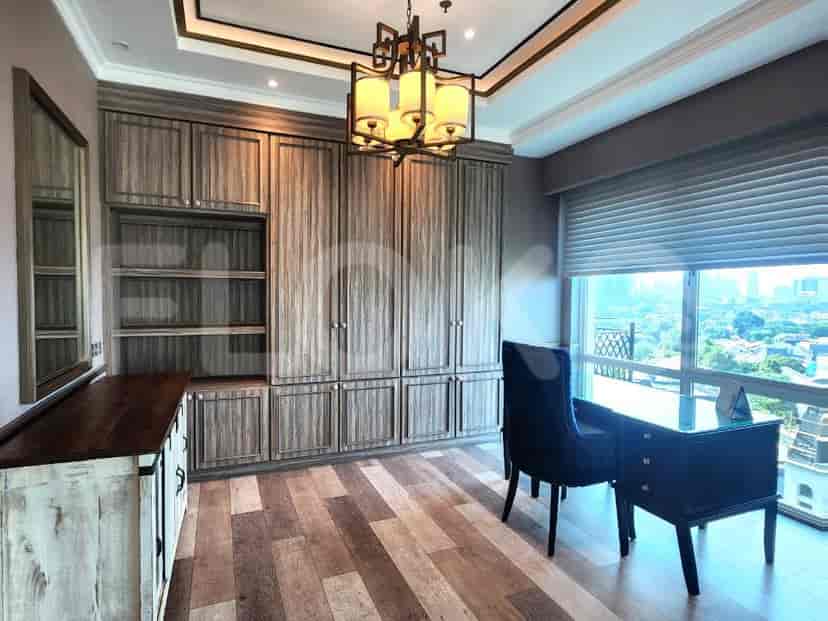 Well-lit home office featuring a large desk, built-in storage, and a black chair with a city view.