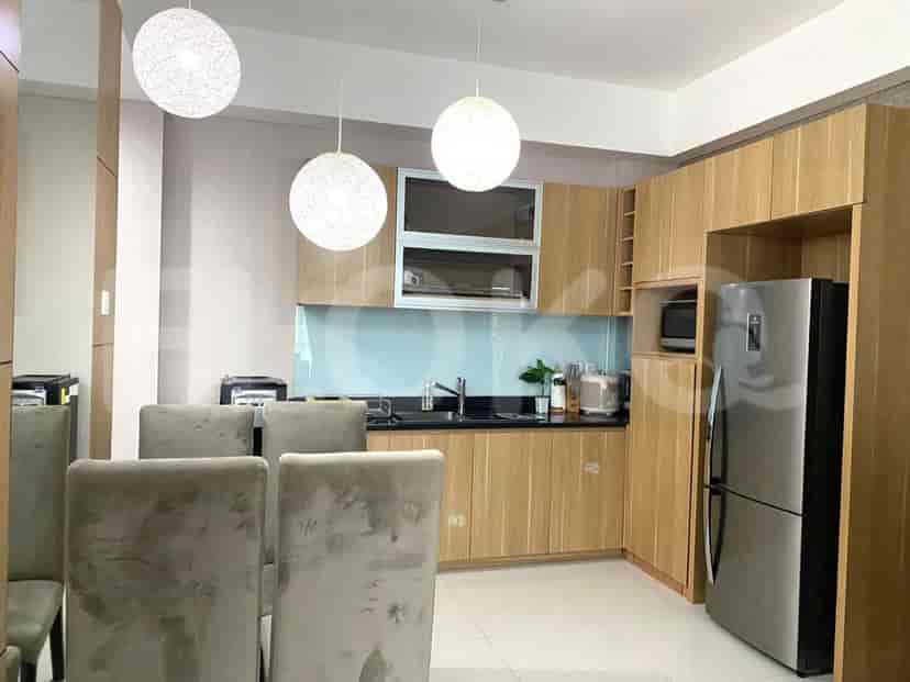 A modern kitchen with wooden cabinets, pendant lights, and a refrigerator.