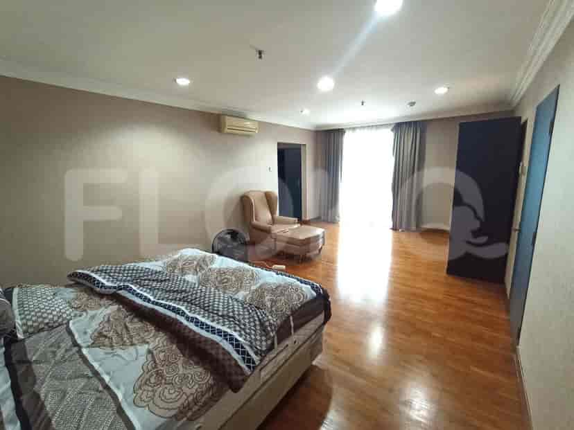 Bedroom with a bed, armchair, and hardwood flooring.
