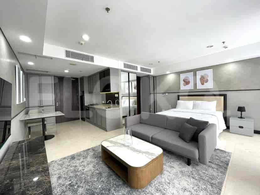 A studio apartment featuring a living space with a sofa and a kitchenette with modern appliances.