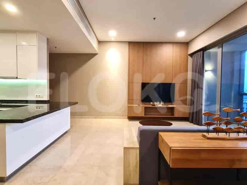 Ruang tamu dengan konsol TV modern, sofa, dan area dapur yang terlihat.