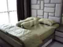 Kamar tidur yang menampilkan tempat tidur dengan seprai hijau dan headboard empuk.