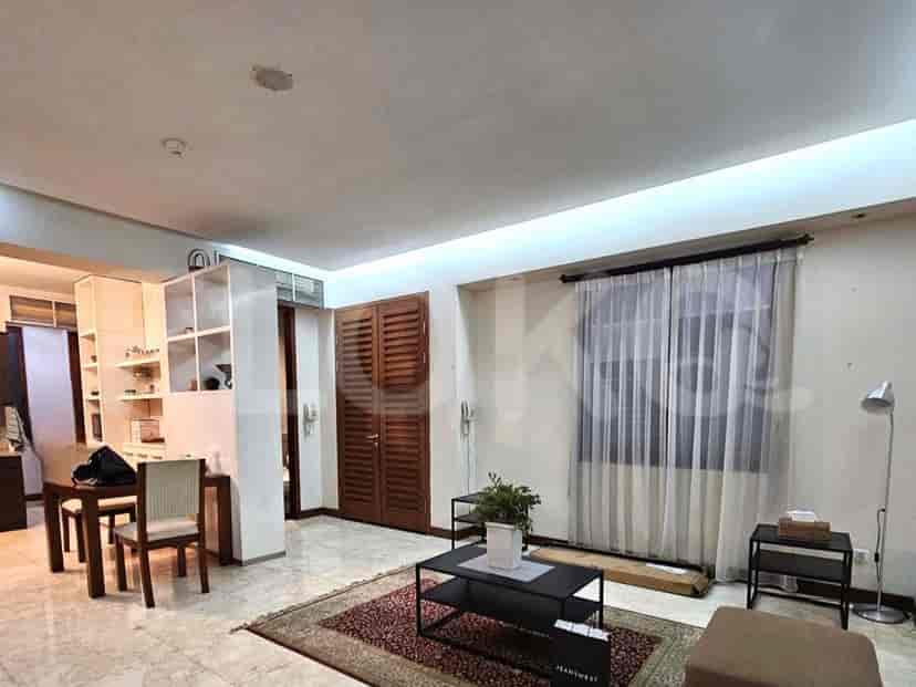 Ruang tamu dengan lemari kayu, karpet bermotif, dan meja kopi hitam.