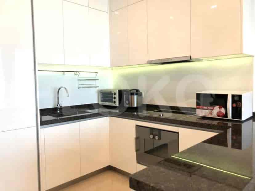 Dapur modern dengan lemari putih, meja hitam, dan peralatan built-in.