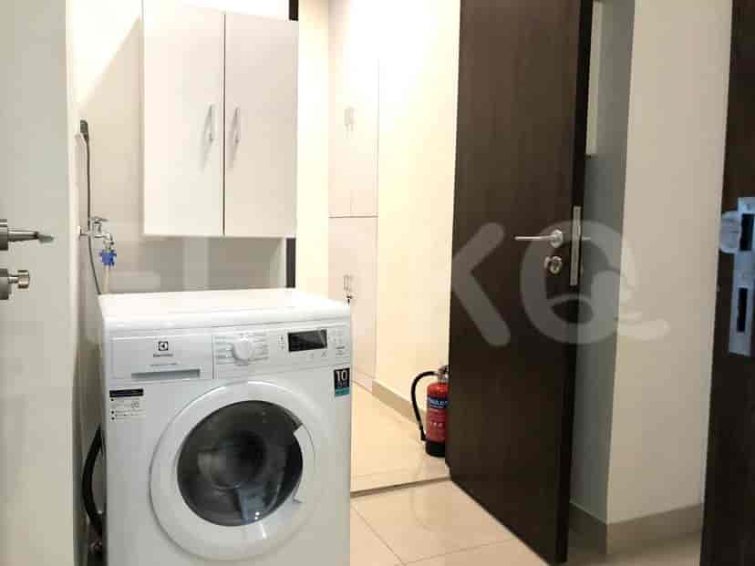 A small laundry room with a washing machine and storage cabinets.